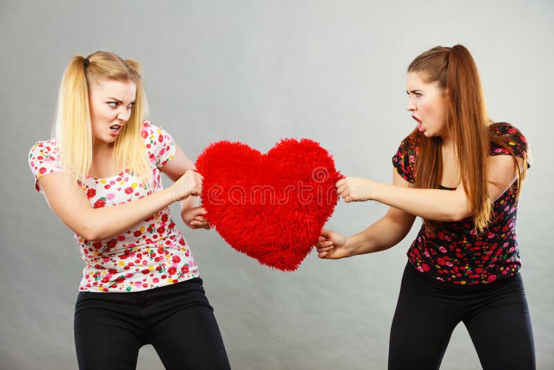 Due donne aggressive che hanno discutono il cuore della tenuta di lotta fotografia stock Due donne aggressive che hanno discutono il cuore della tenuta di lotta fotografia stock