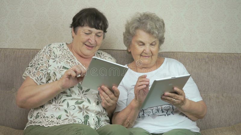 Due donne anziane che tengono le compresse digitali d'argento video d archivio Due donne anziane che tengono le compresse digitali d'argento video d archivio