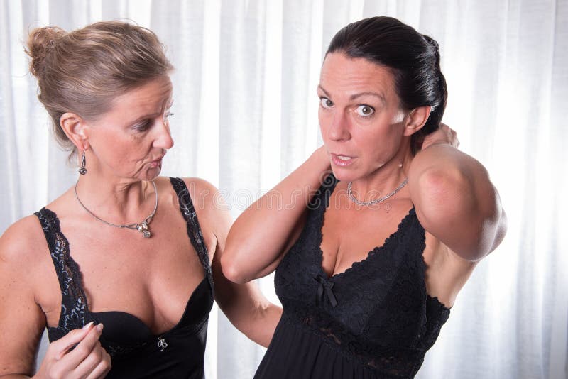 Due donne attraenti che mettono le loro collane sopra immagini stock libere da diritti Due donne attraenti che mettono le loro collane sopra immagini stock libere da diritti