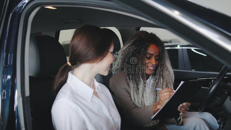 Due donne hanno discusso all'interno di un'auto parcheggiata presso un concessionario durante un pomeriggio soleggiato valutando l stock footage