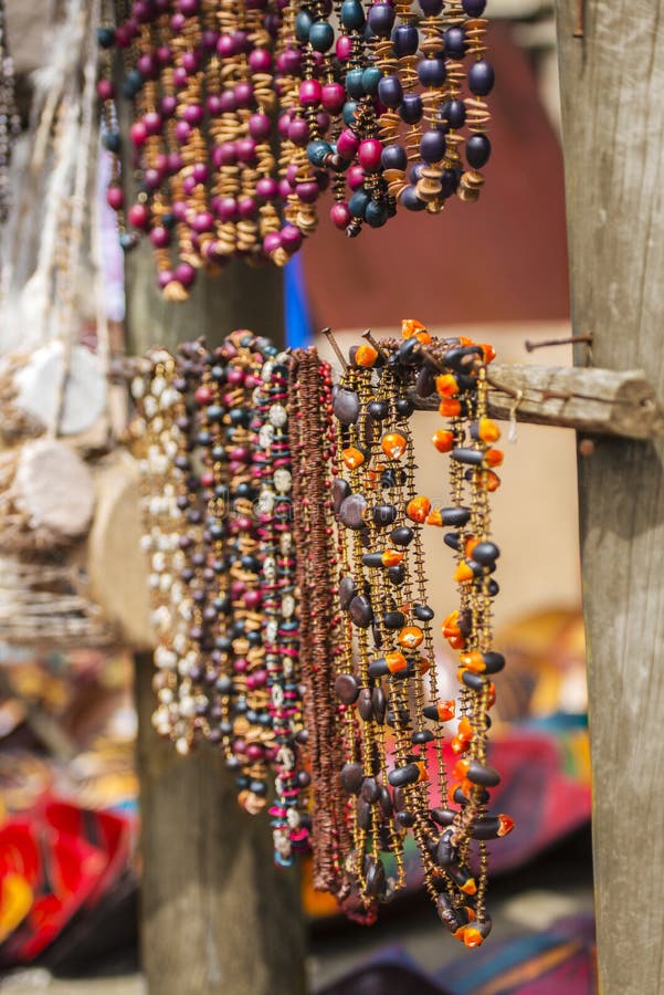 Due file di belle collane africane della perla che pendono dai rami di legno in un mercato dell'aria aperta immagine stock Due file di belle collane africane della perla che pendono dai rami di legno in un mercato dell'aria aperta immagine stock