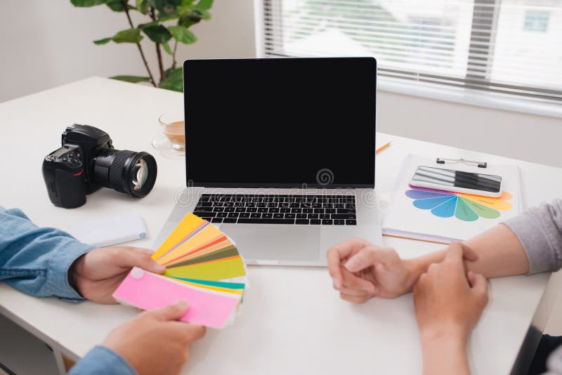 Due fotografi con funzionamento del computer portatile e della macchina fotografica nell'ufficio fotografia stock Due fotografi con funzionamento del computer portatile e della macchina fotografica nell'ufficio fotografia stock