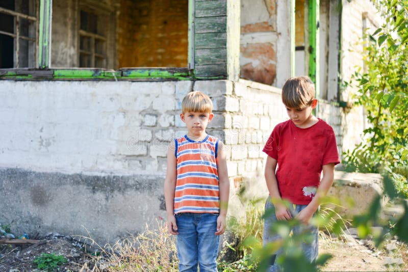 Due fratelli sono in piedi vicino a una casa bruciata, che ha perso la casa a causa di ostilità e disastri naturali immagini stock libere da diritti Due fratelli sono in piedi vicino a una casa bruciata, che ha perso la casa a causa di ostilità e disastri naturali immagini stock libere da diritti