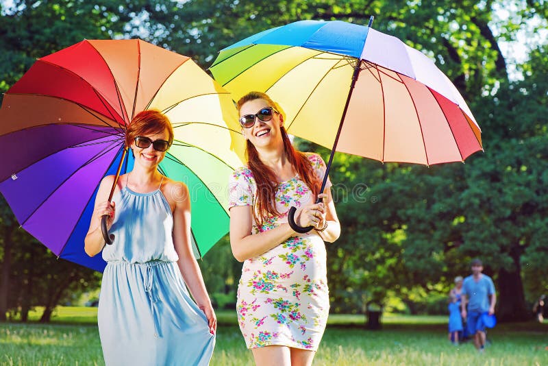 Due giovani donne alla moda che posano con gli ombrelli variopinti fotografie stock