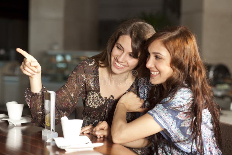 Due giovani donne che bevono caffè ad una barra immagine stock Due giovani donne che bevono caffè ad una barra immagine stock
