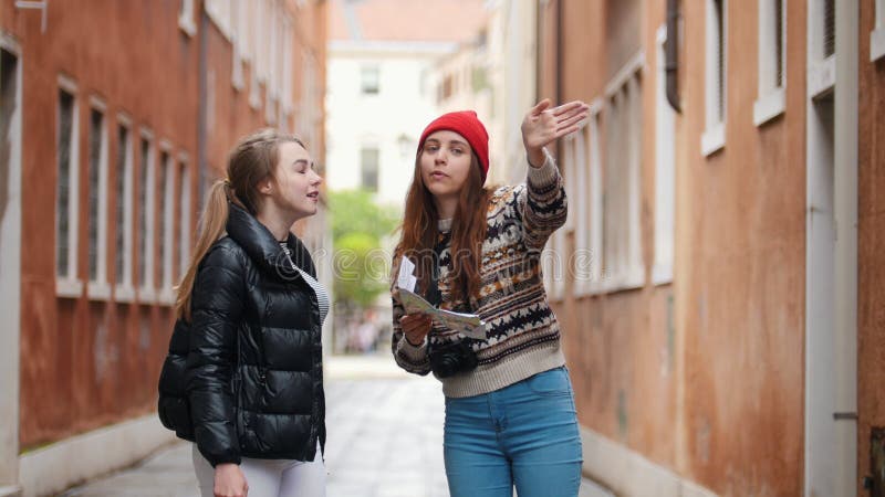 Due giovani donne che stanno sulla via Una donna con una mappa spiega come trovare un'uscita