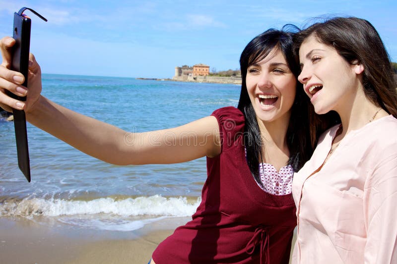 Due giovani donne felici che prendono selfie che sorride sulla spiaggia fotografie stock libere da diritti Due giovani donne felici che prendono selfie che sorride sulla spiaggia fotografie stock libere da diritti