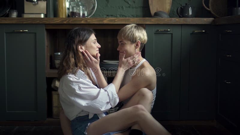 Due giovani donne lesbiche si baciano e si abbracciano mentre sono sedute negli interni moderni. bb stock footage