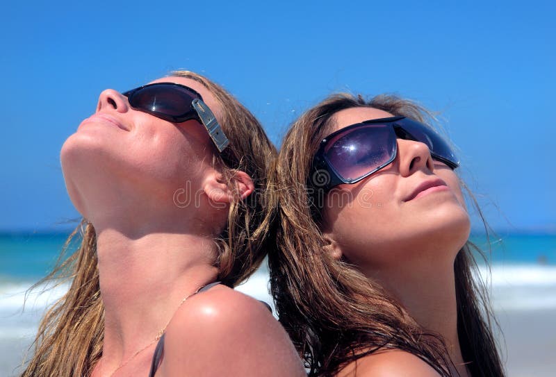 Due giovani donne sexy che prendono il sole su una spiaggia di Sandy immagini stock libere da diritti Due giovani donne sexy che prendono il sole su una spiaggia di Sandy immagini stock libere da diritti