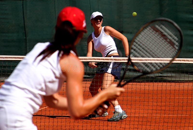 Due giovani giocatori di tennis femminili sportivi che hanno un gioco al sole. immagini stock libere da diritti