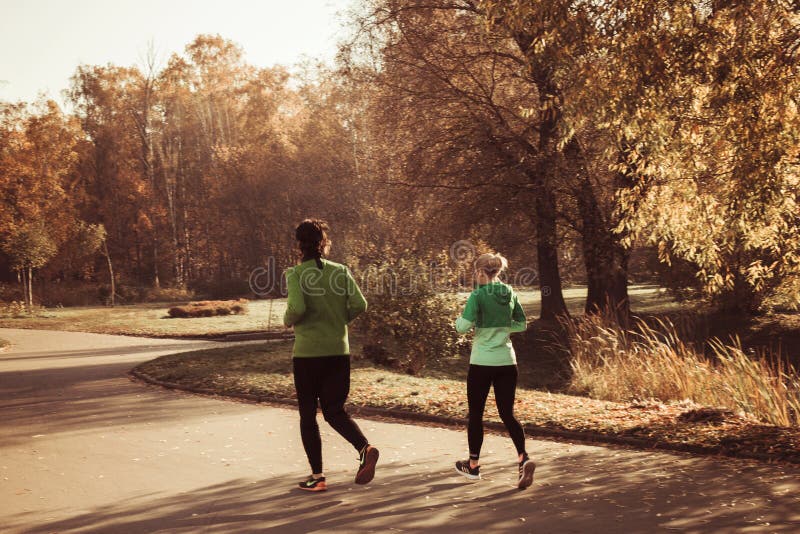 Due giovani nei vestiti di sport stanno pareggiando nel tempo soleggiato caldo di autunno del parco, Mosca, Russia 18 10 2018 immagine stock Due giovani nei vestiti di sport stanno pareggiando nel tempo soleggiato caldo di autunno del parco, Mosca, Russia 18 10 2018 immagine stock