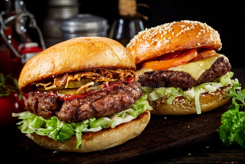 Due hamburger deliziosi del manzo con le guarnizioni dell'insalata fotografia stock libera da diritti
