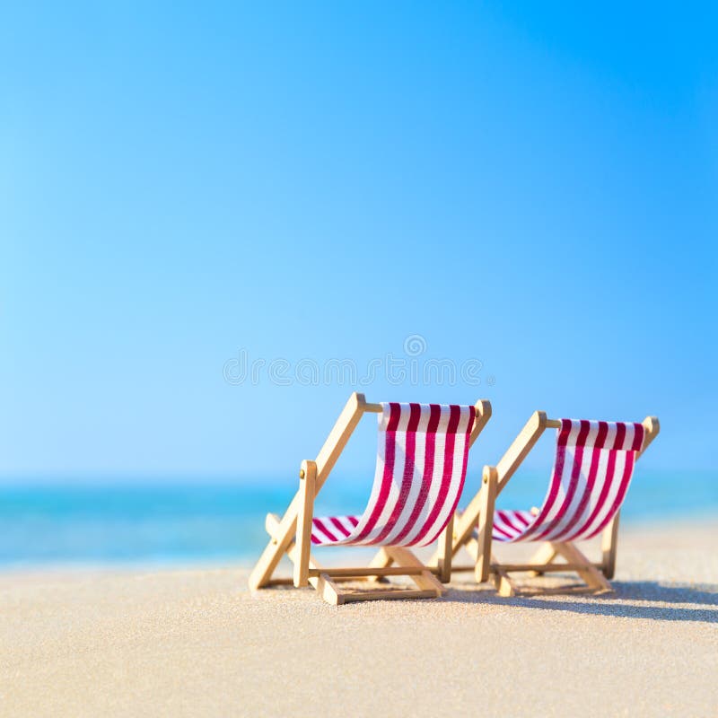 Due hanno barrato i lettini bianchi rosso alla spiaggia tropicale sabbiosa dell'oceano nella h fotografia stock libera da diritti Due hanno barrato i lettini bianchi rosso alla spiaggia tropicale sabbiosa dell'oceano nella h fotografia stock libera da diritti
