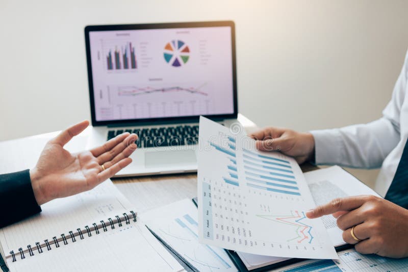 Due impiegati controllano insieme i rendiconti finanziari della società nella stanza di stima fotografie stock Due impiegati controllano insieme i rendiconti finanziari della società nella stanza di stima fotografie stock