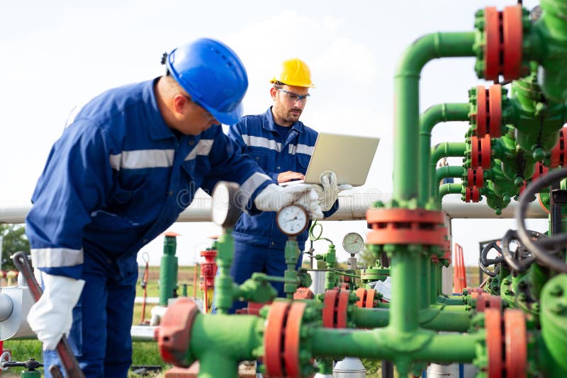 Due lavoratori nel giacimento di petrolio Concetto del gas e del petrolio fotografie stock Due lavoratori nel giacimento di petrolio Concetto del gas e del petrolio fotografie stock