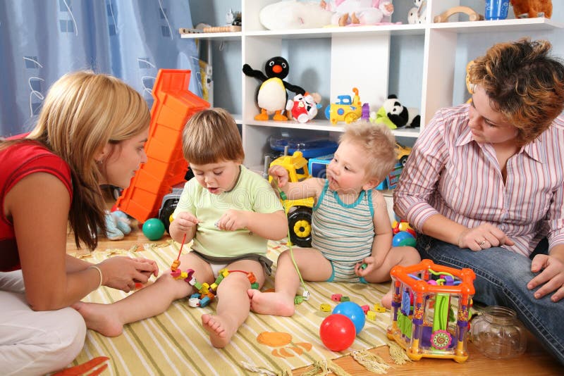 Due madri giocano con i bambini in playroom 2 fotografie stock Due madri giocano con i bambini in playroom 2 fotografie stock