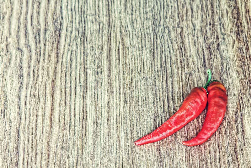 Due peperoncini roventi sul fondo di legno di lerciume Imag tonificato fotografie stock libere da diritti Due peperoncini roventi sul fondo di legno di lerciume Imag tonificato fotografie stock libere da diritti