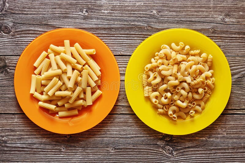 Due piatti di colore con pasta su un fondo di legno immagini stock libere da diritti Due piatti di colore con pasta su un fondo di legno immagini stock libere da diritti