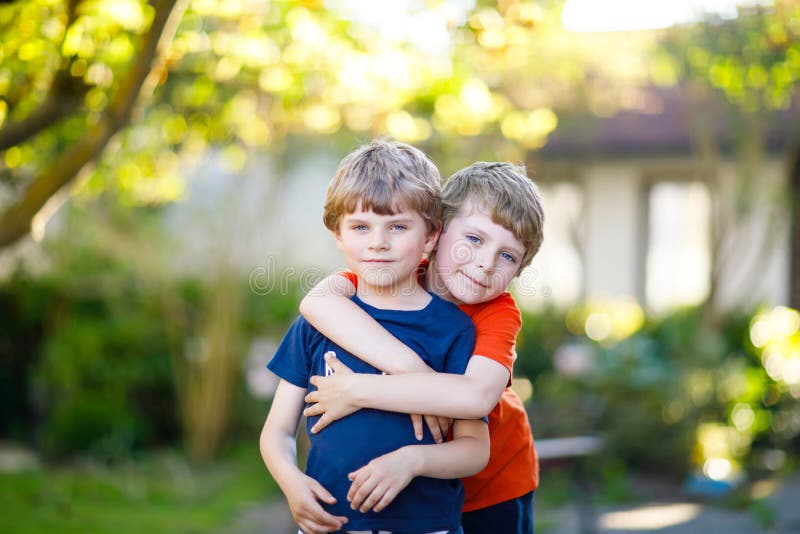 Due poca scuola dell'attivo scherzano i ragazzi, i gemelli ed i fratelli germani abbraccianti il giorno di estate immagini stock libere da diritti Due poca scuola dell'attivo scherzano i ragazzi, i gemelli ed i fratelli germani abbraccianti il giorno di estate immagini stock libere da diritti