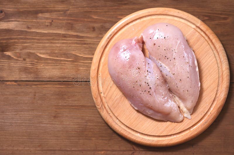 Due raccordi crudi del pollo stanno alla destra sotto forma di un cuore su un bordo di legno contro un fondo dell'albero immagine stock libera da diritti Due raccordi crudi del pollo stanno alla destra sotto forma di un cuore su un bordo di legno contro un fondo dell'albero immagine stock libera da diritti