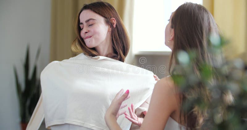 Due ragazze adolescenti e carine sedute sul divano insieme, sorella che mostra un nuovo acquisto di camicia bianca, indossando ab