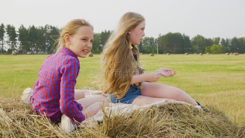 Due ragazze adolescenti sedute su un pagliaio in campagna in campagna Le ragazze felici chiacchierano sul fieno al