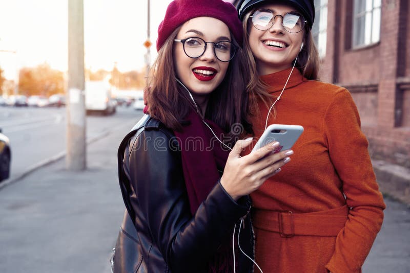 Due ragazze allegre che ballano mentre ascoltando la musica sullo smartphone, città all'aperto fotografie stock libere da diritti Due ragazze allegre che ballano mentre ascoltando la musica sullo smartphone, città all'aperto fotografie stock libere da diritti
