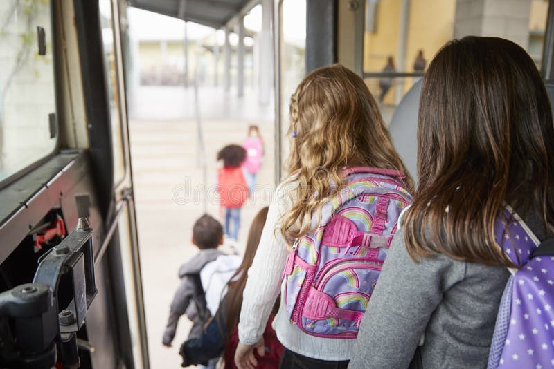 Due ragazze che aspettano dietro i loro amici per scendere scuolabus