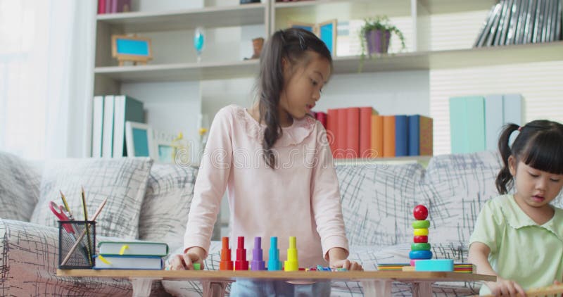 Due ragazze che giocano con il giocattolo educativo di legno variopinto a casa stock footage