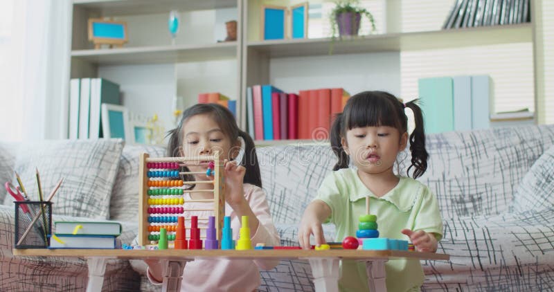 Due ragazze che giocano con il giocattolo educativo di legno variopinto a casa archivi video
