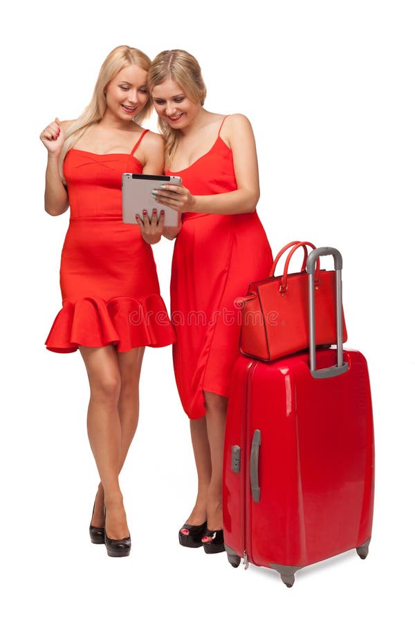 Due ragazze che indossano il rosso si veste con la grandi valigia e borsa e tabl fotografia stock libera da diritti Due ragazze che indossano il rosso si veste con la grandi valigia e borsa e tabl fotografia stock libera da diritti