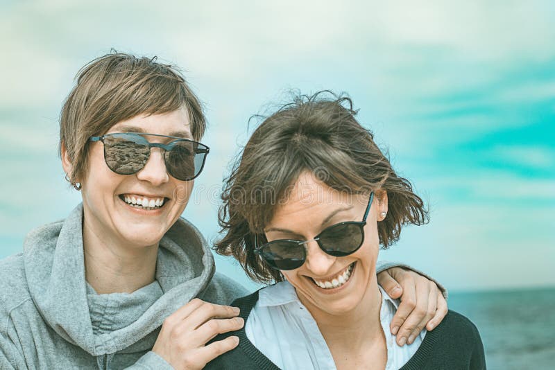 Two girls smiling and having fun on the beach. Concept of friendship. Healthy and cheerful lifestyle. Two girls smiling and having fun on the beach. Concept of friendship. Healthy and cheerful lifestyle