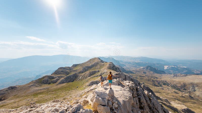 Due ragazze con zaini camminano lungo il sentiero di montagna immagine stock