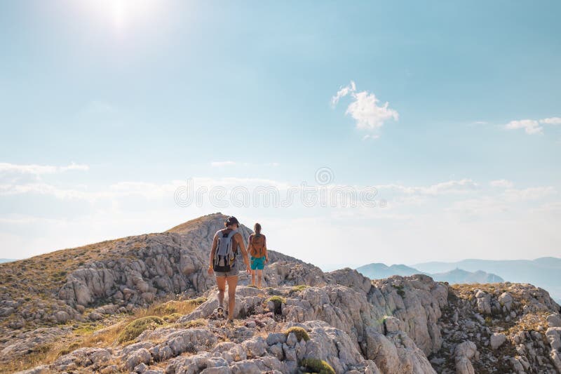 Due ragazze con zaini camminano lungo il sentiero di montagna immagini stock