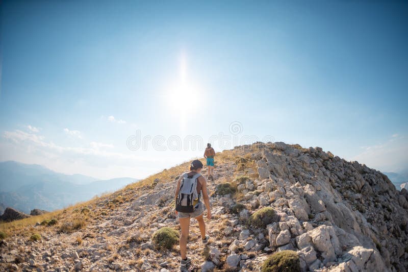 Due ragazze con zaini camminano lungo il sentiero di montagna fotografia stock libera da diritti