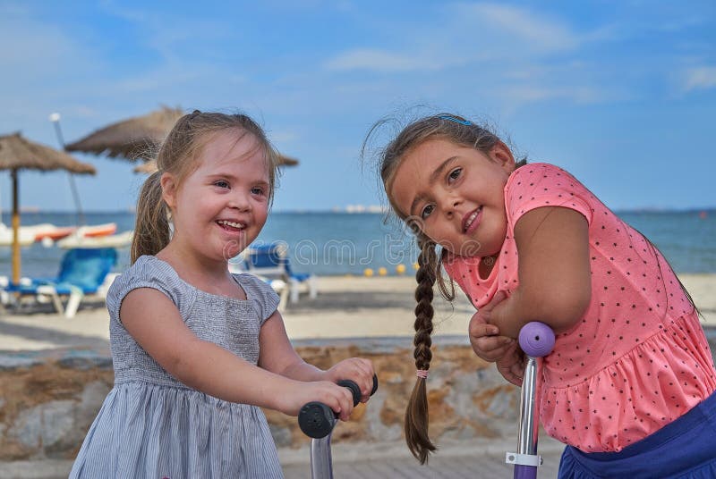 Due ragazze felici sui motorini dalla spiaggia immagine stock libera da diritti Due ragazze felici sui motorini dalla spiaggia immagine stock libera da diritti