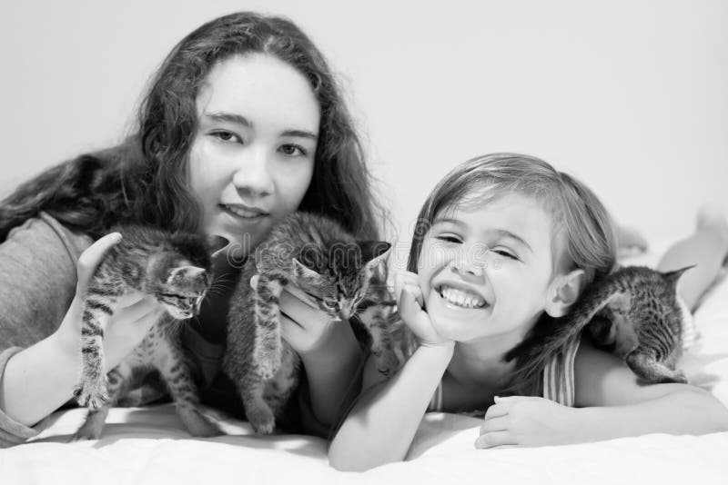 Due ragazze sorridenti e tre gattini svegli del soriano fotografia stock libera da diritti Due ragazze sorridenti e tre gattini svegli del soriano fotografia stock libera da diritti