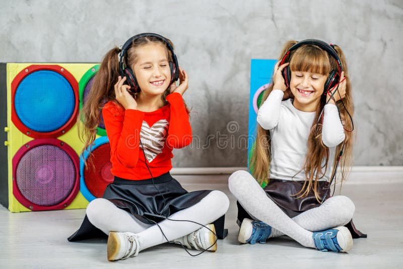 Due ragazze stanno ascoltando musica sulle cuffie Musica di concetto, r fotografia stock Due ragazze stanno ascoltando musica sulle cuffie Musica di concetto, r fotografia stock