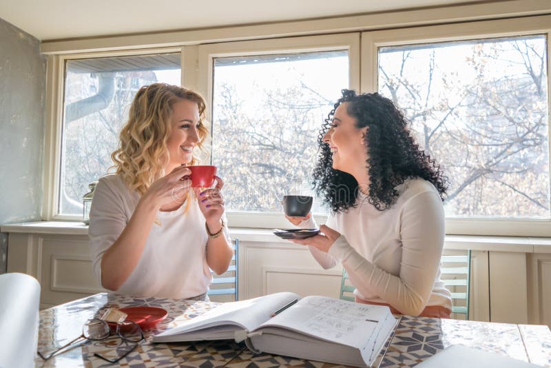 Due ragazze stanno bevendo il caffè e stanno ridendo in caffè immagini stock libere da diritti Due ragazze stanno bevendo il caffè e stanno ridendo in caffè immagini stock libere da diritti