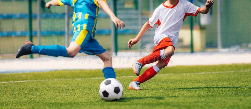 Due ragazzi di calcio che prendono a calci la palla nelle squadre opposte. momento di calcio a duello di calcio. giovani calciator fotografia stock libera da diritti