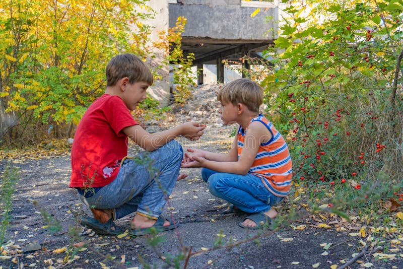 Due ragazzi si siedono l'uno di fronte all'altro nel parco e comunicano tra di loro in due fotografia stock libera da diritti