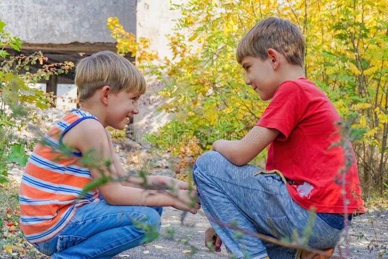 Due ragazzi si siedono l'uno di fronte all'altro nel parco e comunicano tra di loro in due immagine stock