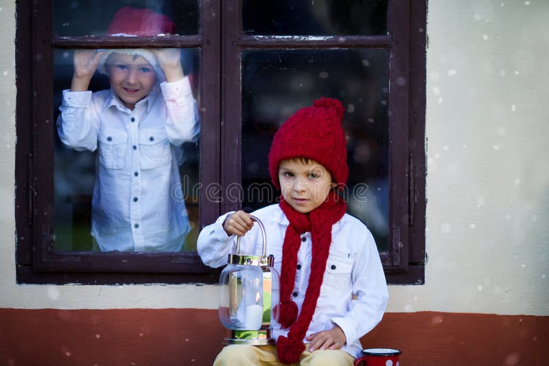 Due ragazzi svegli, fratelli, guardando attraverso una finestra, S aspettante fotografie stock libere da diritti Due ragazzi svegli, fratelli, guardando attraverso una finestra, S aspettante fotografie stock libere da diritti