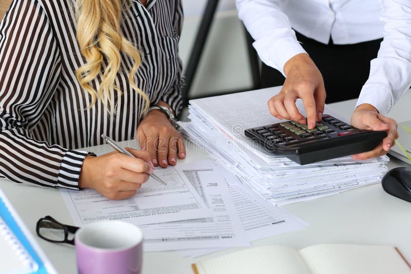 Due ragionieri femminili che contano sul calcolatore immagini stock Due ragionieri femminili che contano sul calcolatore immagini stock