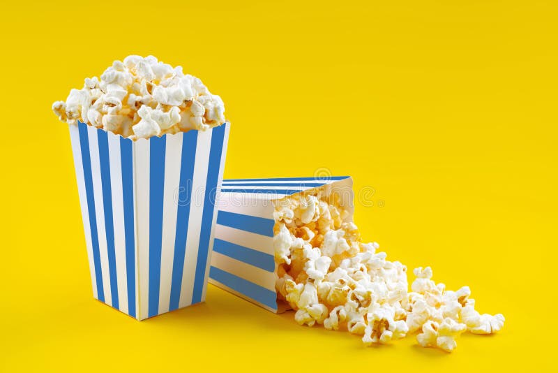 Due secchi di cartone a strisce bianche azzurre con popcorn di formaggio saporito isolati su fondo giallo immagini stock libere da diritti