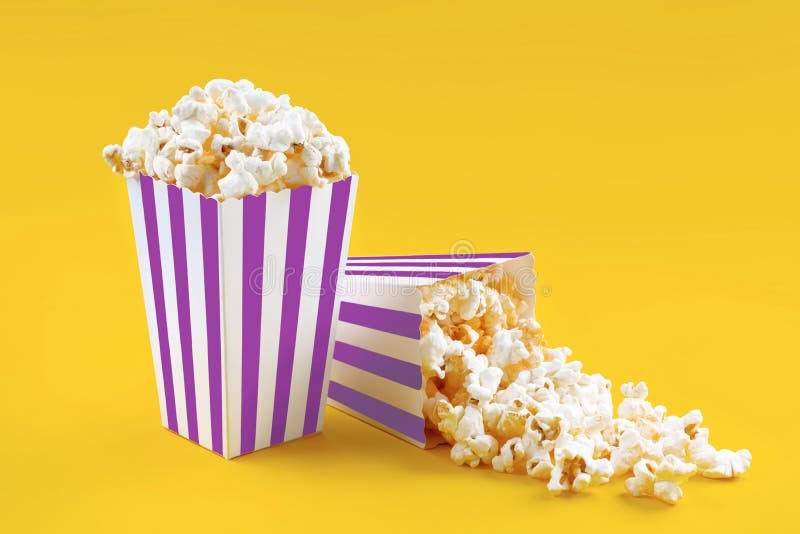 Due secchi di cartone a strisce bianche con formaggio gustoso e popcorn isolati su fondo giallo immagini stock libere da diritti