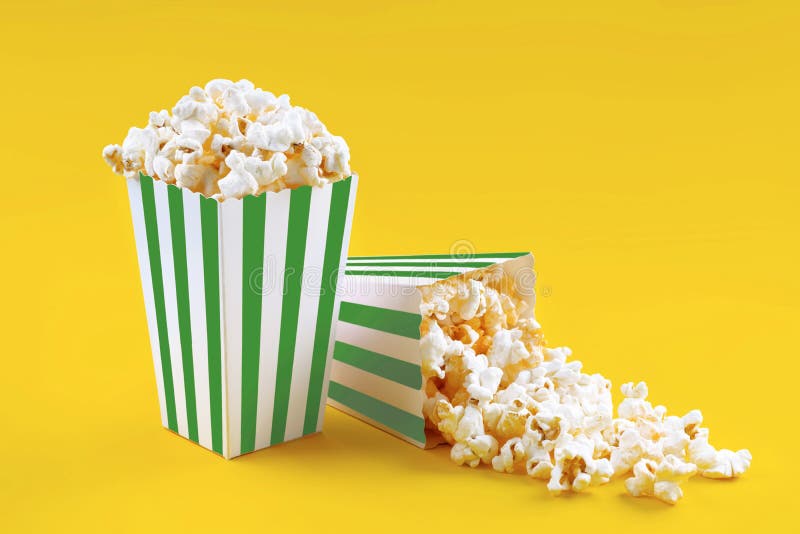 Due secchi di cartone a strisce bianche verdi con popcorn di formaggio saporito isolati su fondo giallo immagine stock libera da diritti