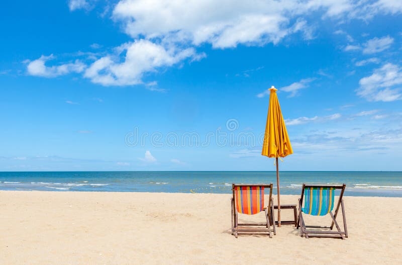 Due sedie di spiaggia variopinte con l'ombrello di sole sulla bella spiaggia w fotografia stock libera da diritti
