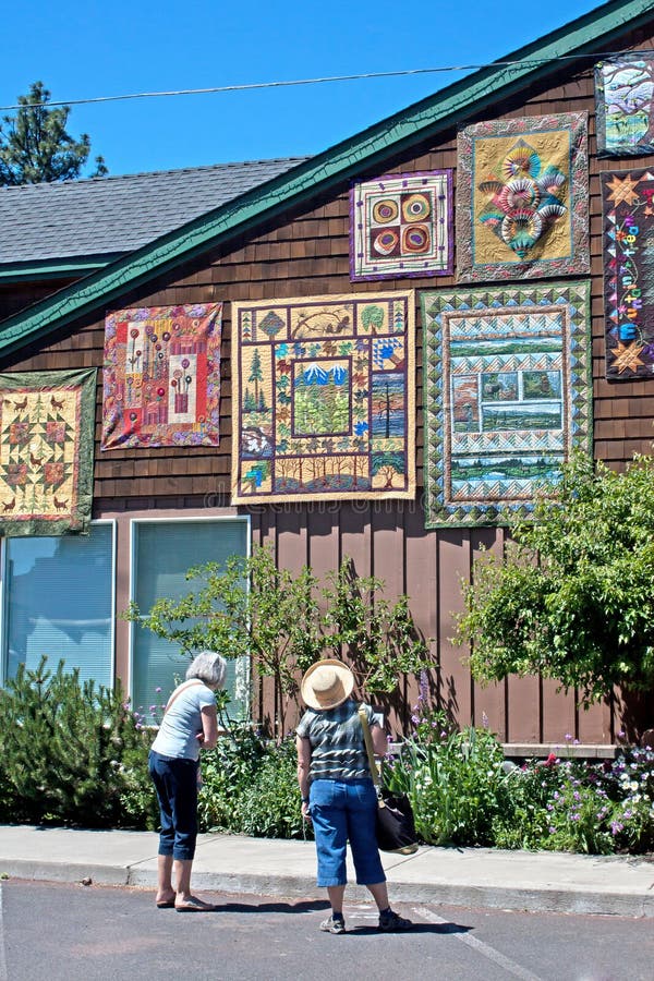 Two ladies enjoy looking at quilts hung on a building at the 2011 outdoor quilt show in Sisters, Oregon. Two ladies enjoy looking at quilts hung on a building at the 2011 outdoor quilt show in Sisters, Oregon