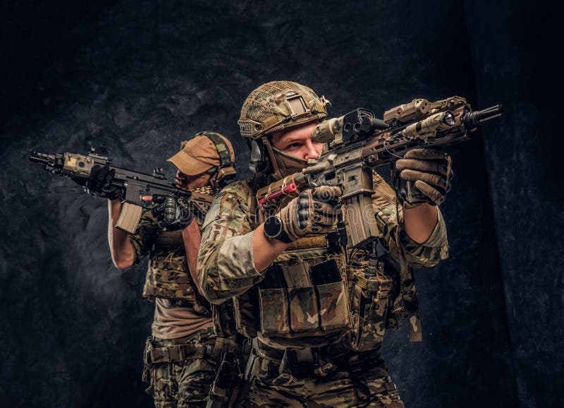 Due soldati delle forze speciali in attrezzatura protettiva piena che tiene i fucili di assalto e che punta sugli obiettivi Foto fotografia stock Due soldati delle forze speciali in attrezzatura protettiva piena che tiene i fucili di assalto e che punta sugli obiettivi Foto fotografia stock
